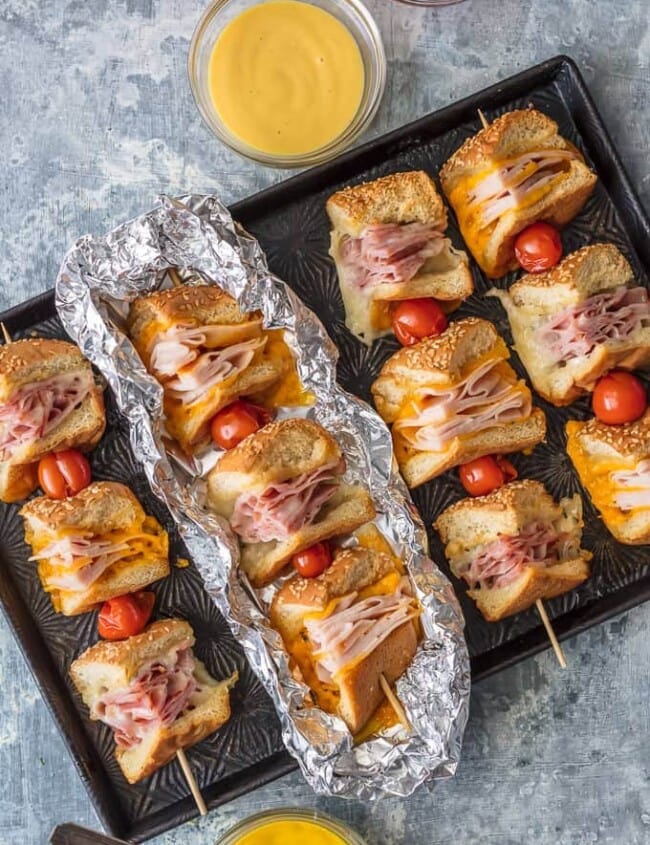 These Cheesy Garlic Butter Sandwich Skewers are a twist on an old classic. Cheesy Ham, Turkey, and Roast Beef sandwiches drizzled with garlic butter and cooked to perfection in foil packets; such a fun and delicious lunch or dinner!