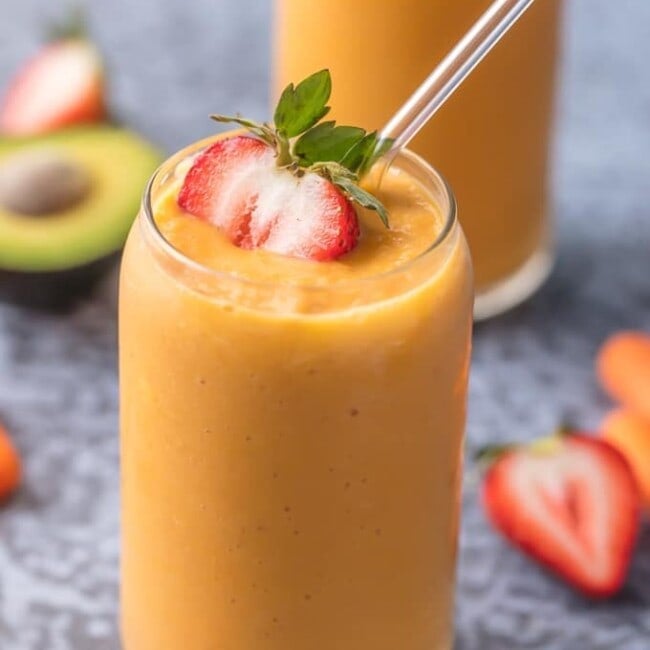 glowing skin smoothie in a glass garnished with a strawberry and straw