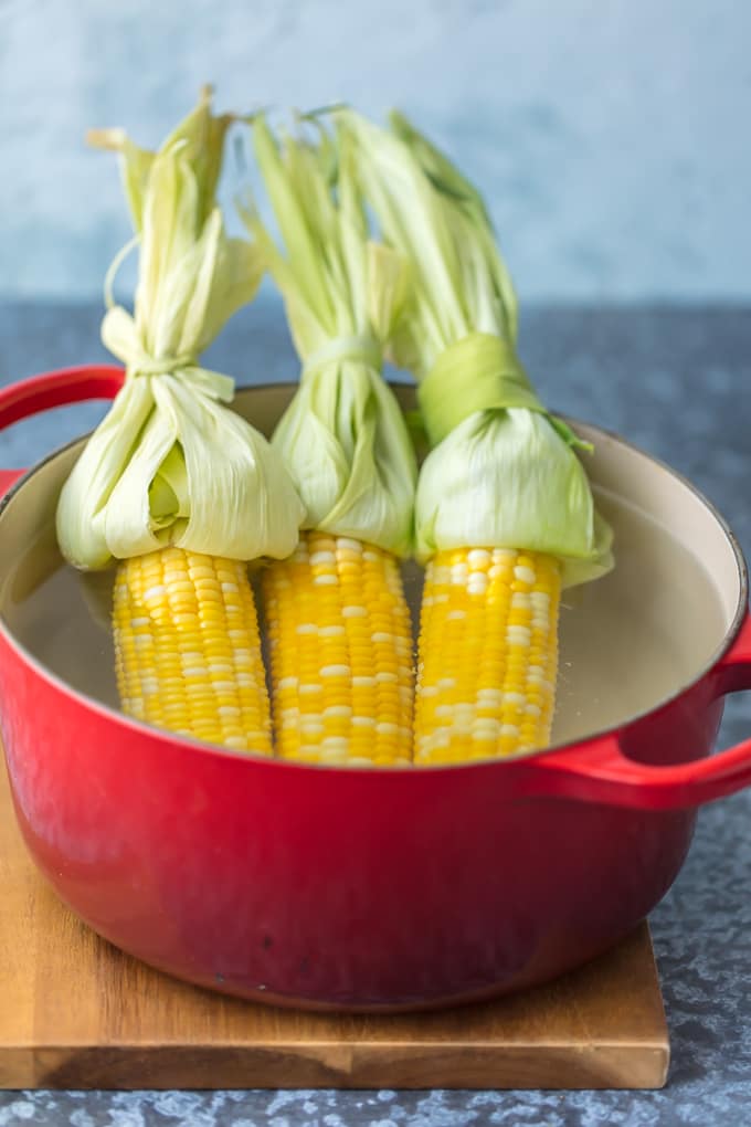 Boiling corn on the cob in a large red pot