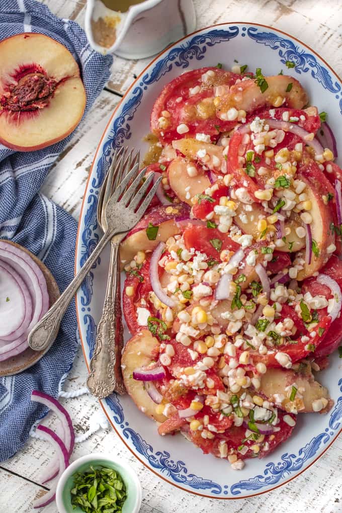 Serving plate with corn, peaches, tomatoes, onion, feta, and mint