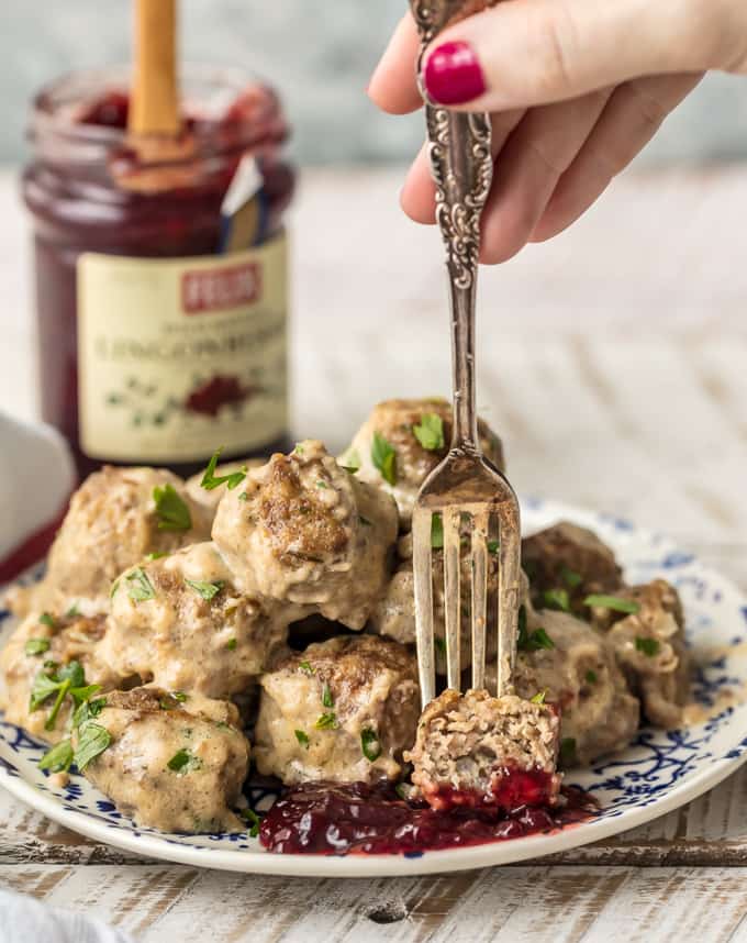 fork picking up a Swedish meatball and dipping it in lingonberry jam