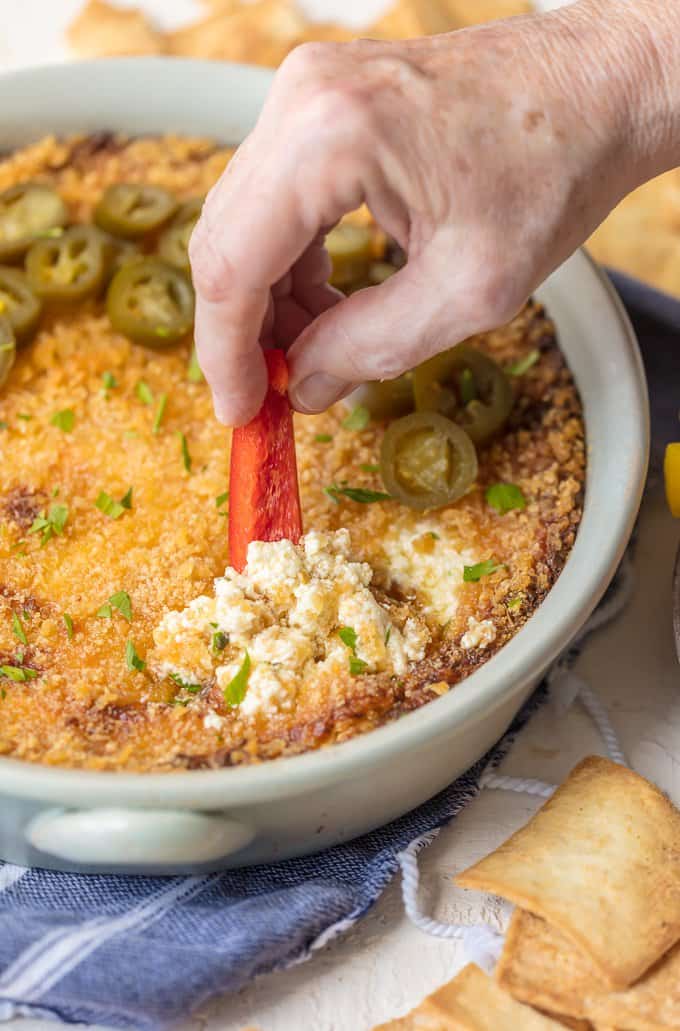 Dipping a red bell pepper stick into jalapeno popper dip