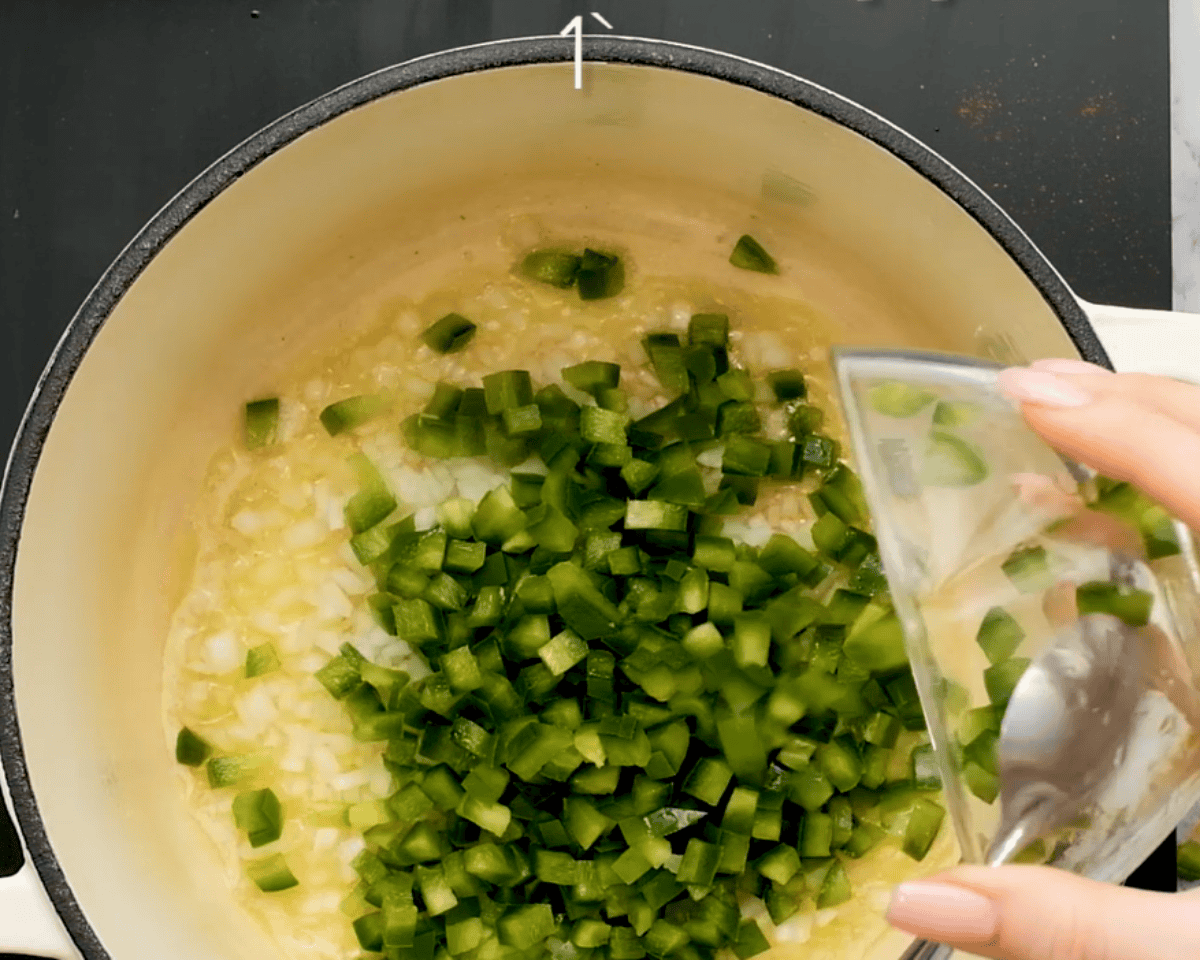 Cooking onions and green peppers in a pot.
