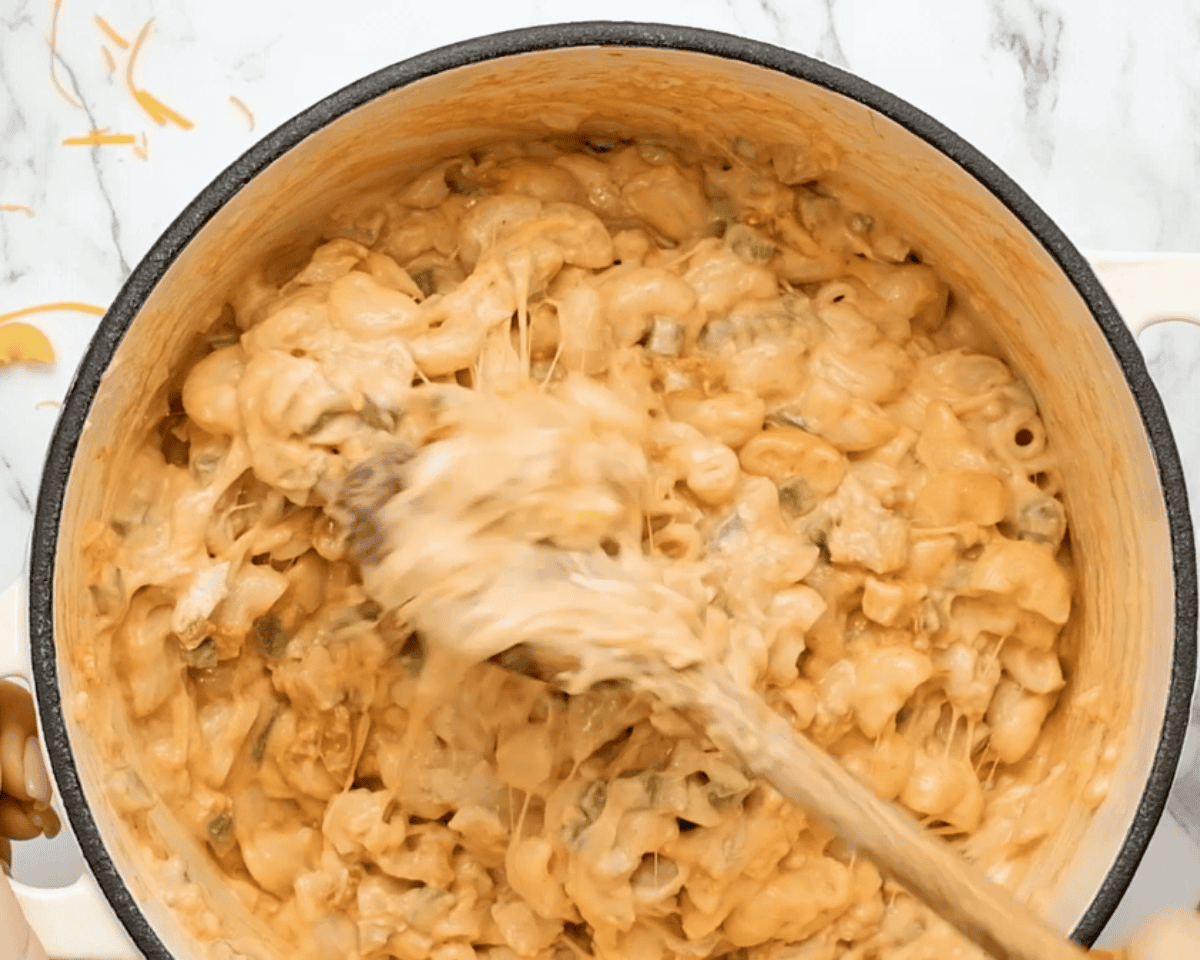Adding pasta to the pot with the King Ranch chicken mac and cheese ingredients.