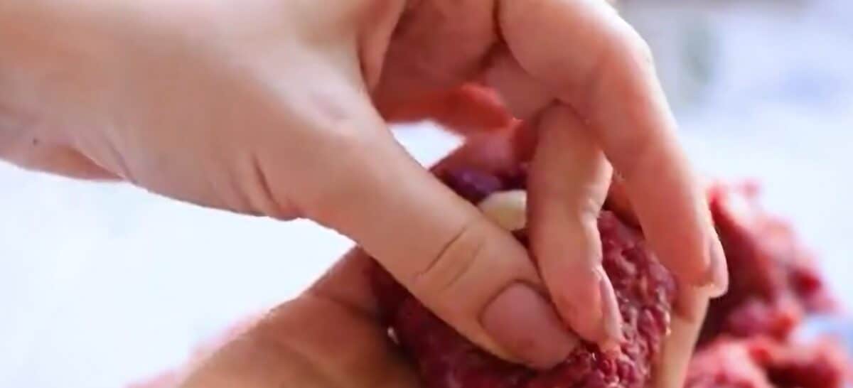 Forming the meatball around the mozzarella pearls.