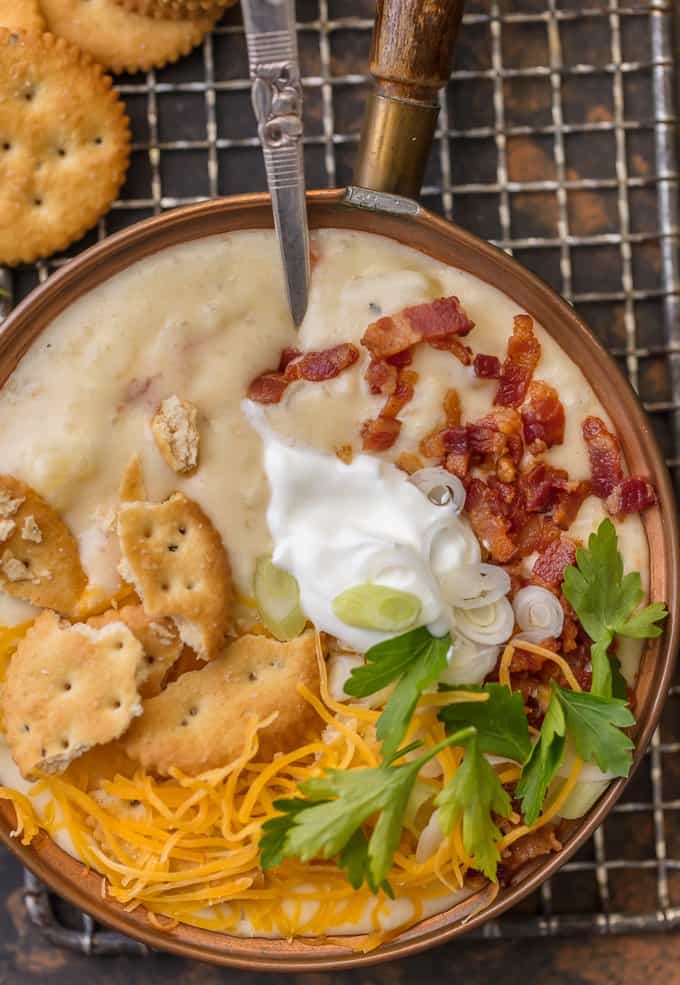 close up on soup topped with sour cream, cheese, bacon, crackers, and cilantro