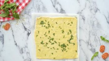 a square of pizza dough brushed with garlic basil butter.