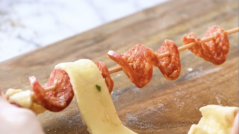 folded pepperoni threaded on a bamboo skewer.