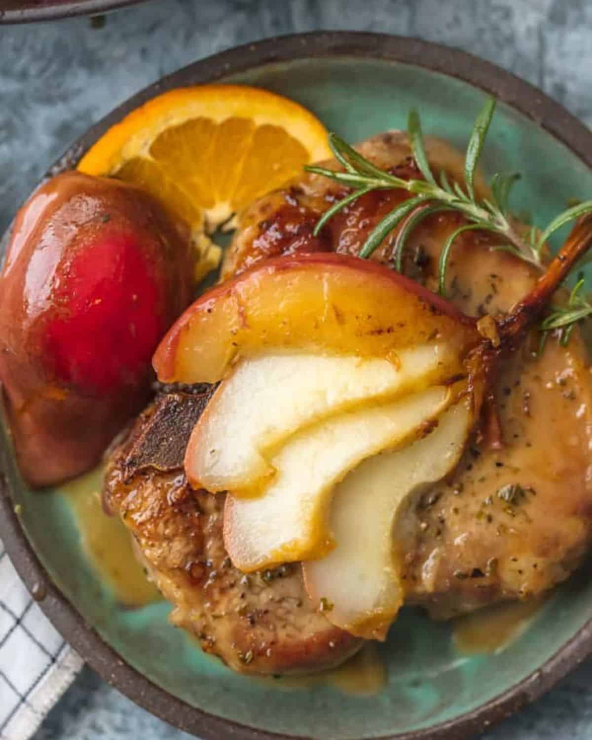 Honey bourbon pear pork chops are the perfect fall comfort food.We are obsessed with these HERB CRUSTED HONEY BOURBON PEAR PORK CHOPS! They are rubbed with fragrant herbs and are the perfect mix of savory and sweet. The best pork chops recipe for fall! Honey pork chop with a cooked pear and a sprig of rosemary.