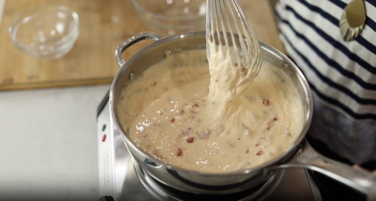 beer cheese dip with tomatoes in a saucepan.
