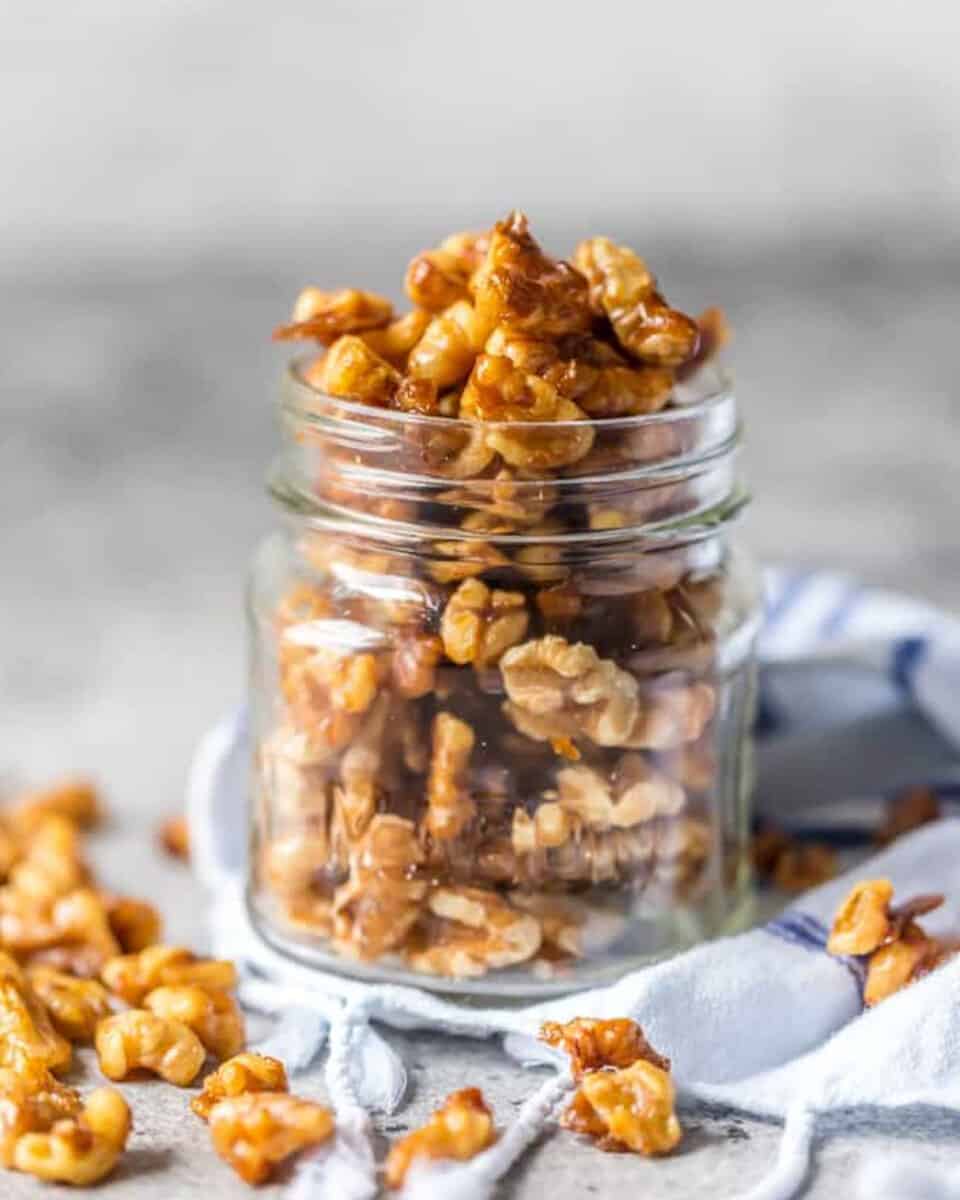 Homemade candied walnuts in a jar on a rustic table.
