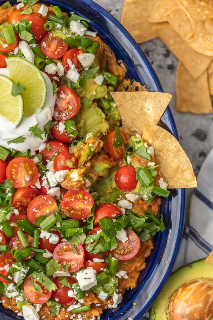 Layered bean dip filled with refried beans, tomatoes, guacamole, cheese, and more