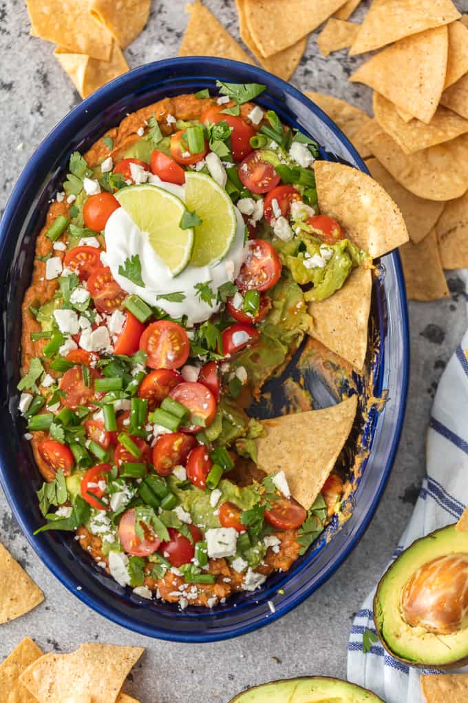 Layered Bean Dip Recipe in large dish, surrounded by tortilla chips