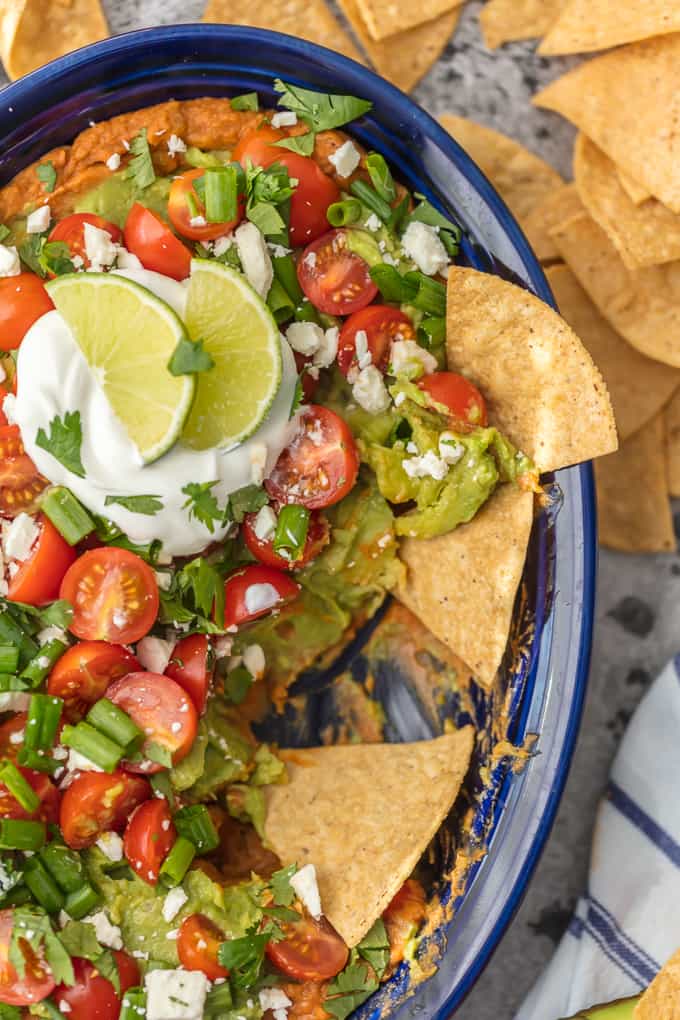 This CRAZY GOOD GUACAMOLE BEAN DIP is layered with spicy refried beans, guacamole, green onion, tomatoes, feta, and more. SO delicious and made in minutes!