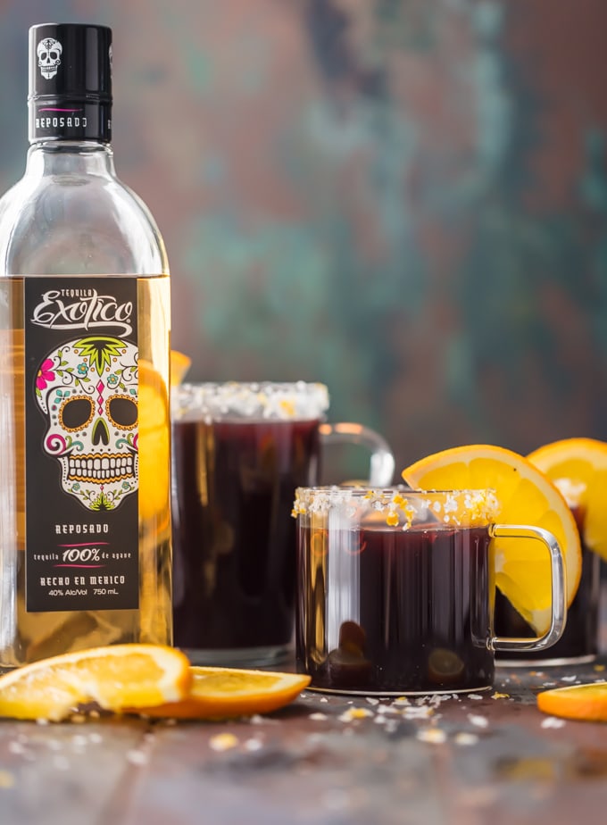 SPICED MULLED WINE MARGARITAS garnished with fresh orange slices next to a bottle of Exotico tequila.