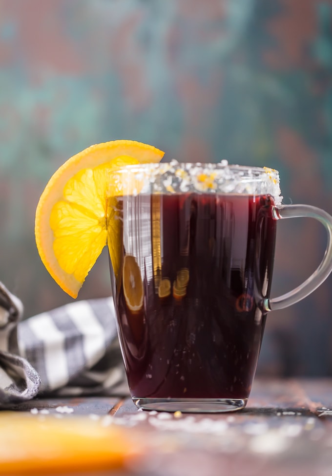 tall clear mug with a MULLED WINE MARGARITA, rimmed with an orange slice