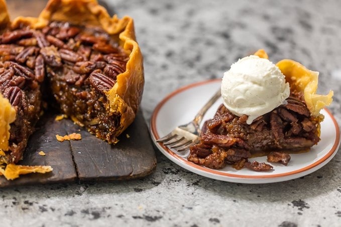 slice of pecan pie on a plate next to a full pie