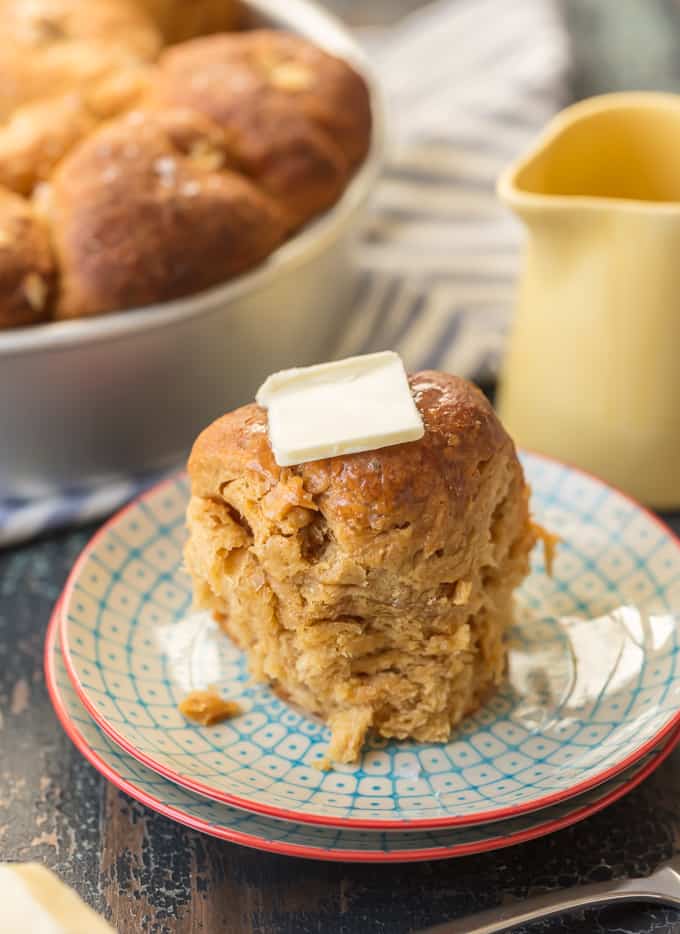 oatmeal bread roll on a small plate, topped with a pat of butter