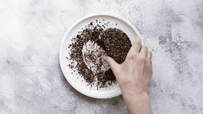 A person is sprinkling peppercorns on a plate, accompanied by a luscious brandy cream sauce.