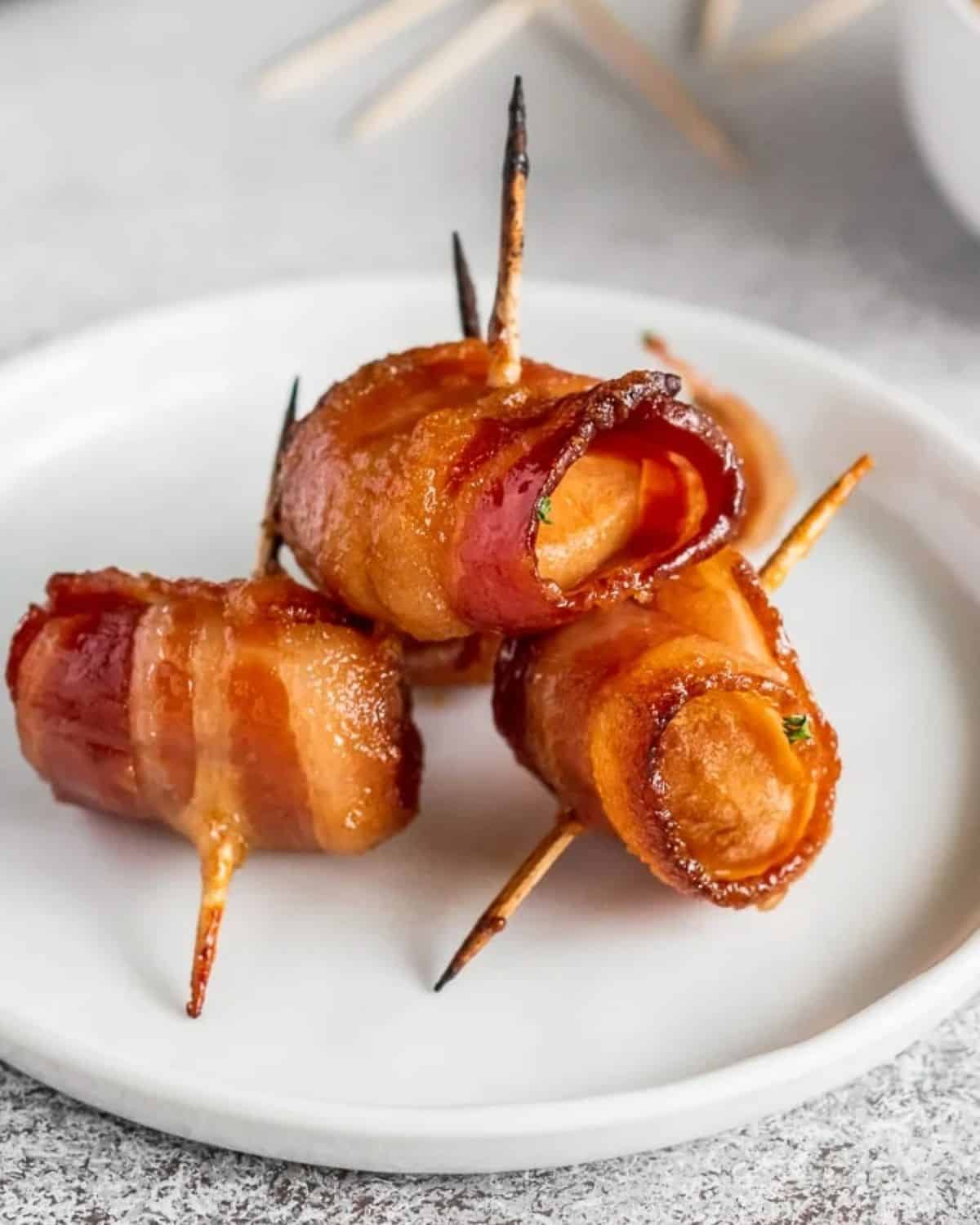 Bacon wrapped water chestnuts on a white plate.