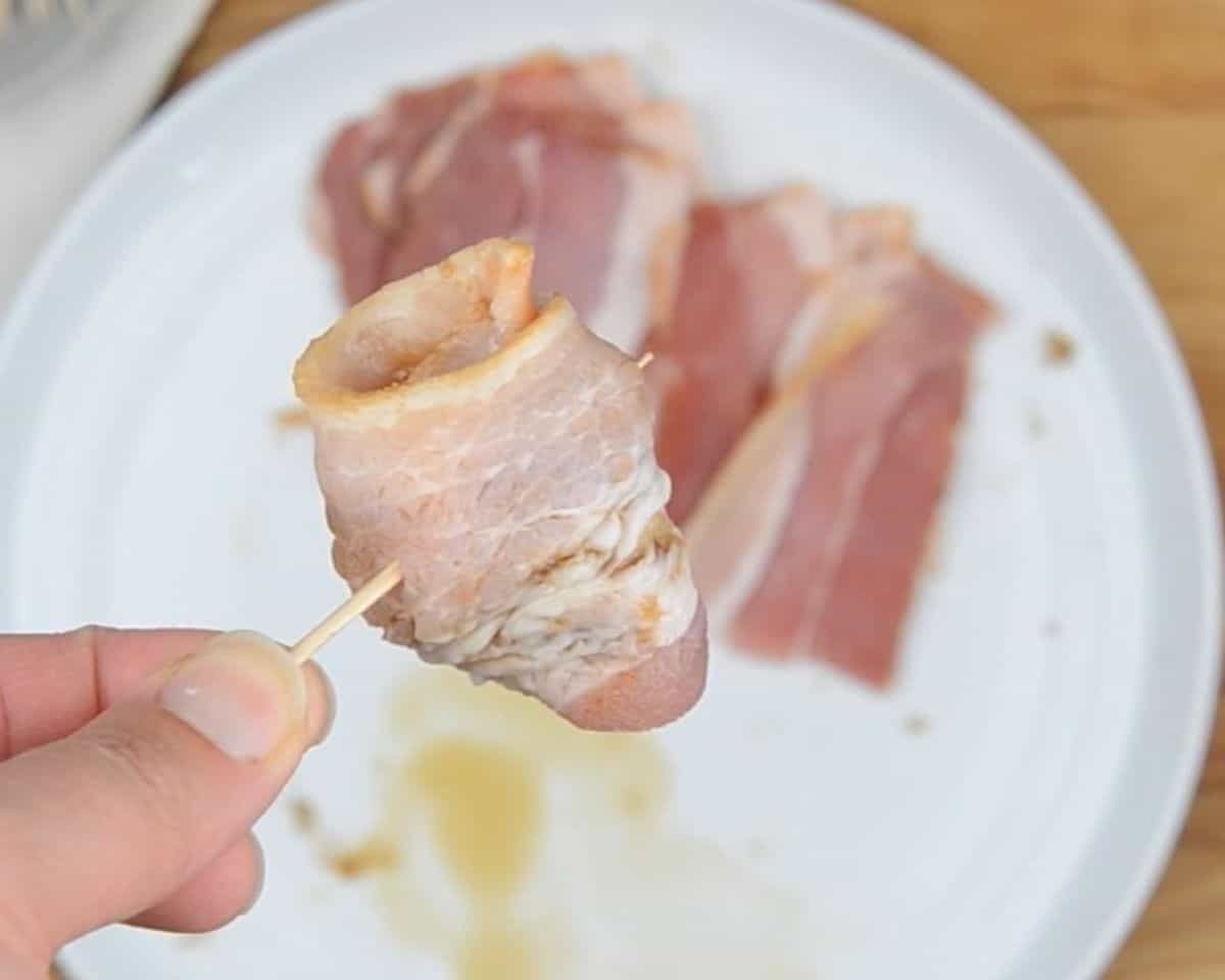 A bacon wrapped water chestnut being held together with a toothpick.