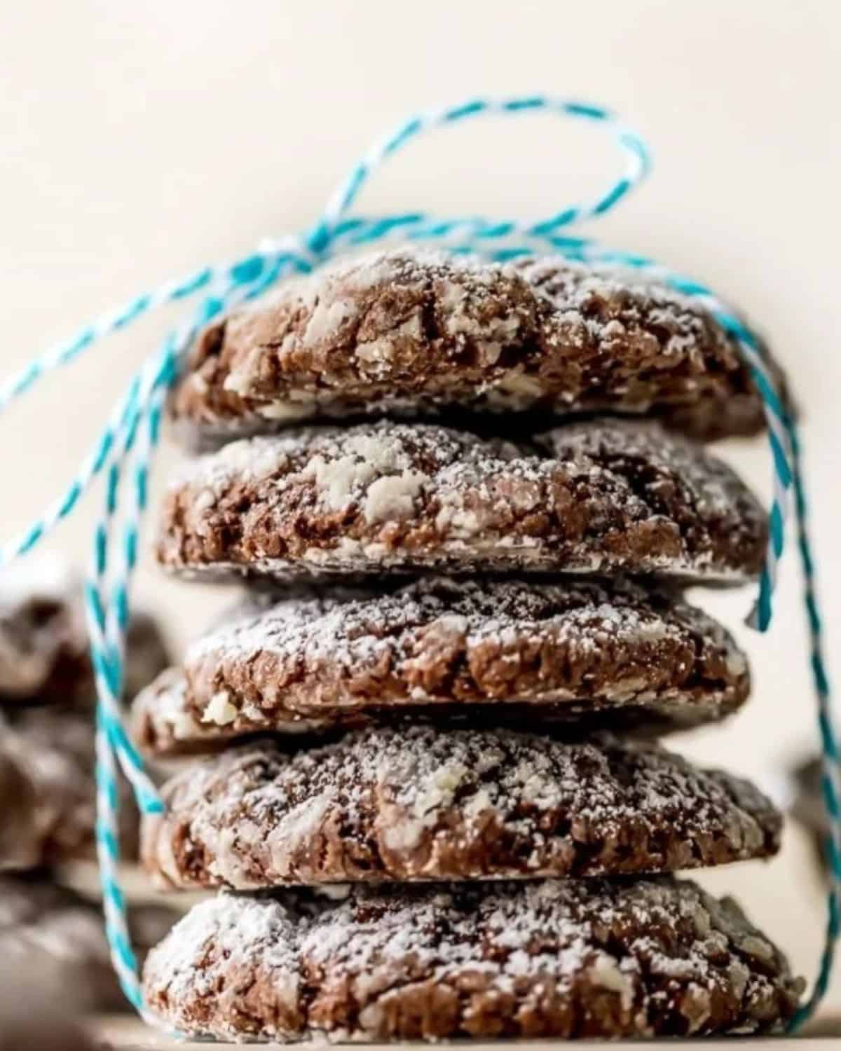 GOOEY BUTTER COOKIES are the perfect combination of gooey butter cake, chocolate brownies, and soft cookies! Being from St. Louis, we are big fans of gooey butter cake. It's even better when you add chocolate and make it into cookie form! Chocolate Cake Cookies just got an upgrade. This Chocolate Gooey Butter Cookies Recipe is one of my favorite Christmas cookie recipes! A stack of chocolate gooey butter cookies tied together with a blue string.