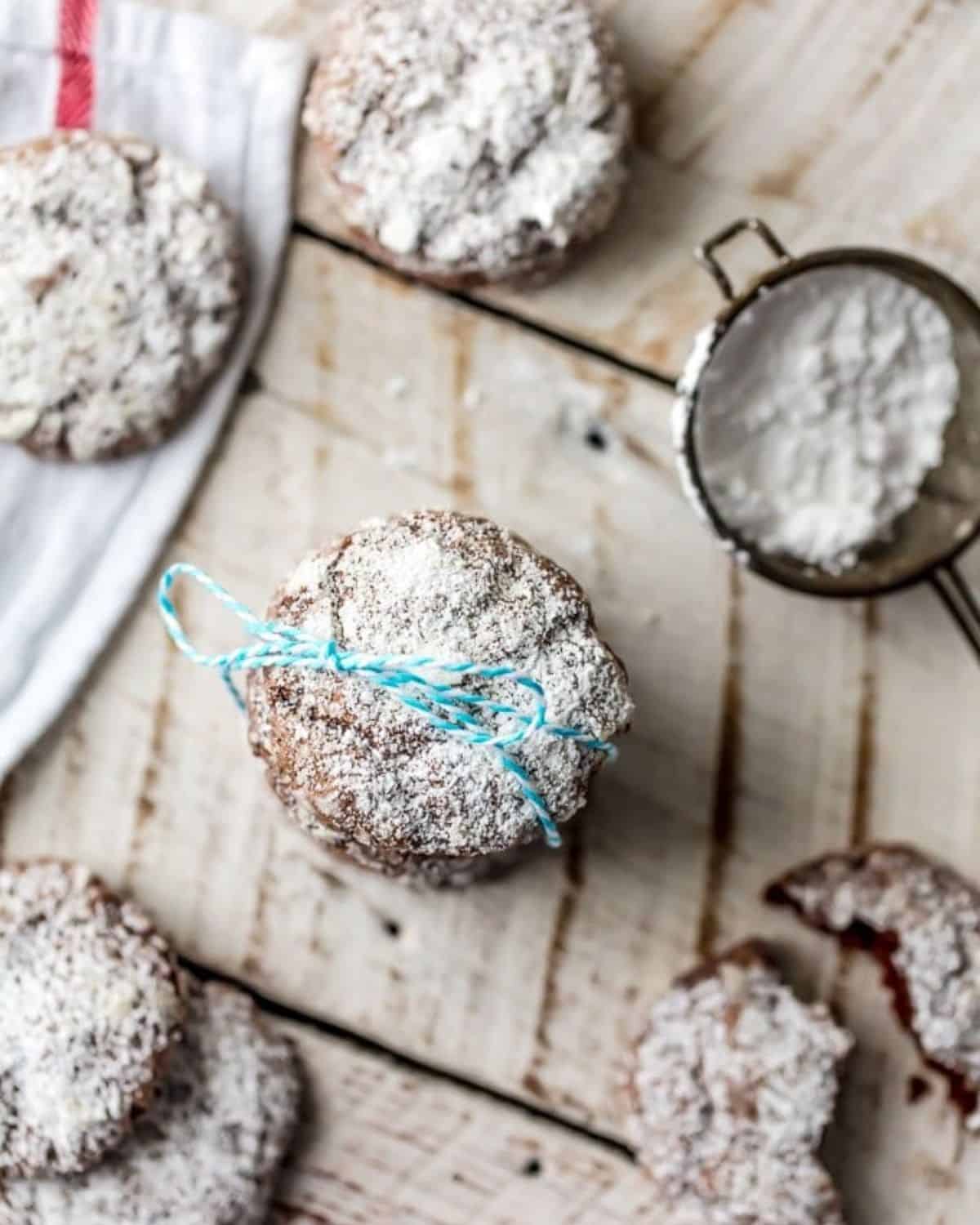 CHOCOLATE GOOEY BUTTER CAKE COOKIES are the perfect combination of gooey butter cake and soft cookies! We are big fans of gooey butter cake. It's even better when you add chocolate and bake it into cookie form! One of my favorite Christmas cookie recipes! #cookies #christmas #chocolate #gooeybuttercake Chocolate gooey butter cookies in a stack tied with blue string.