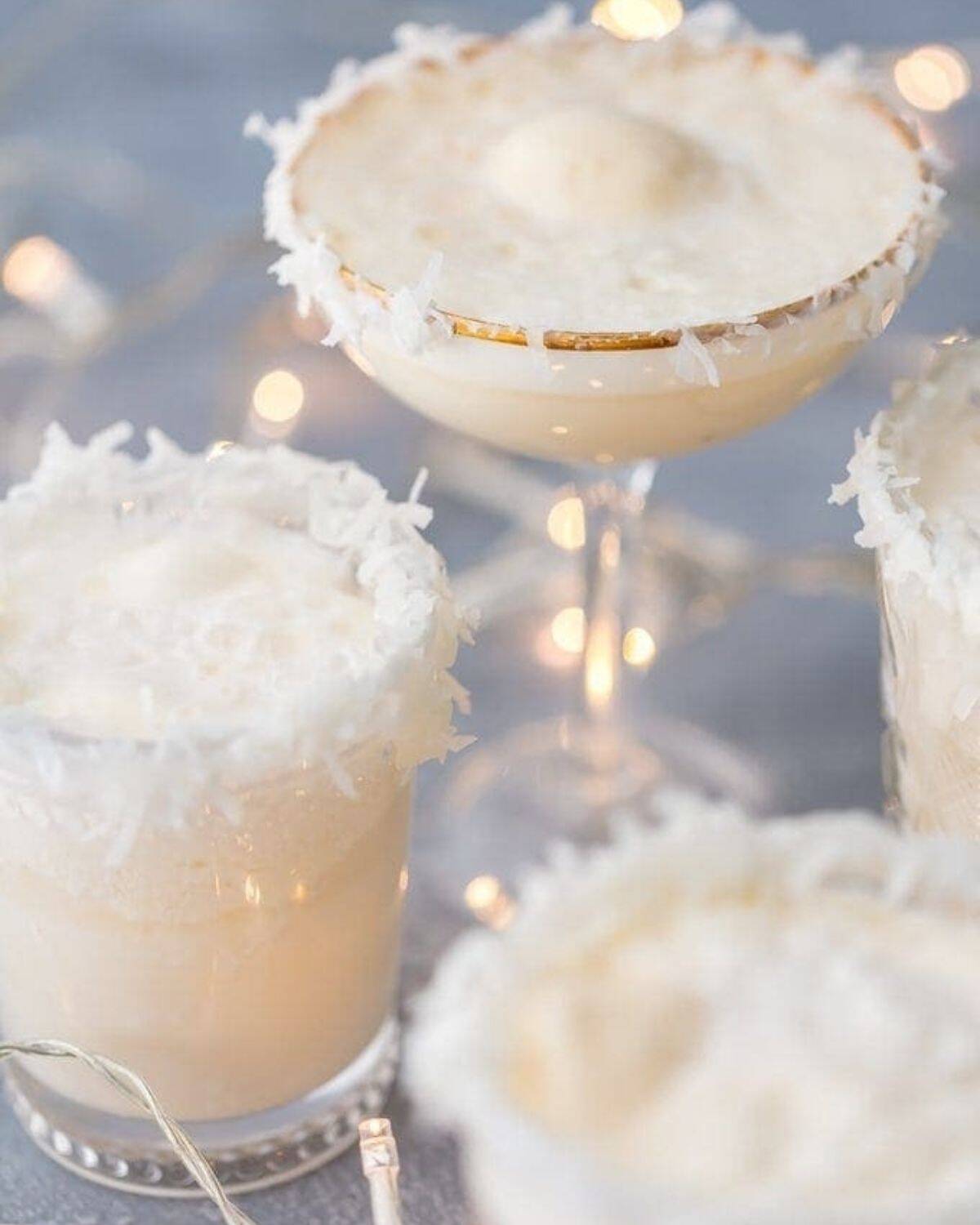 three glasses of festive snow punch topped with coconut flakes