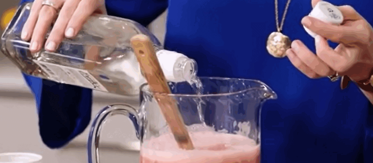 Adding tequila to the strawberry margarita punch. 
