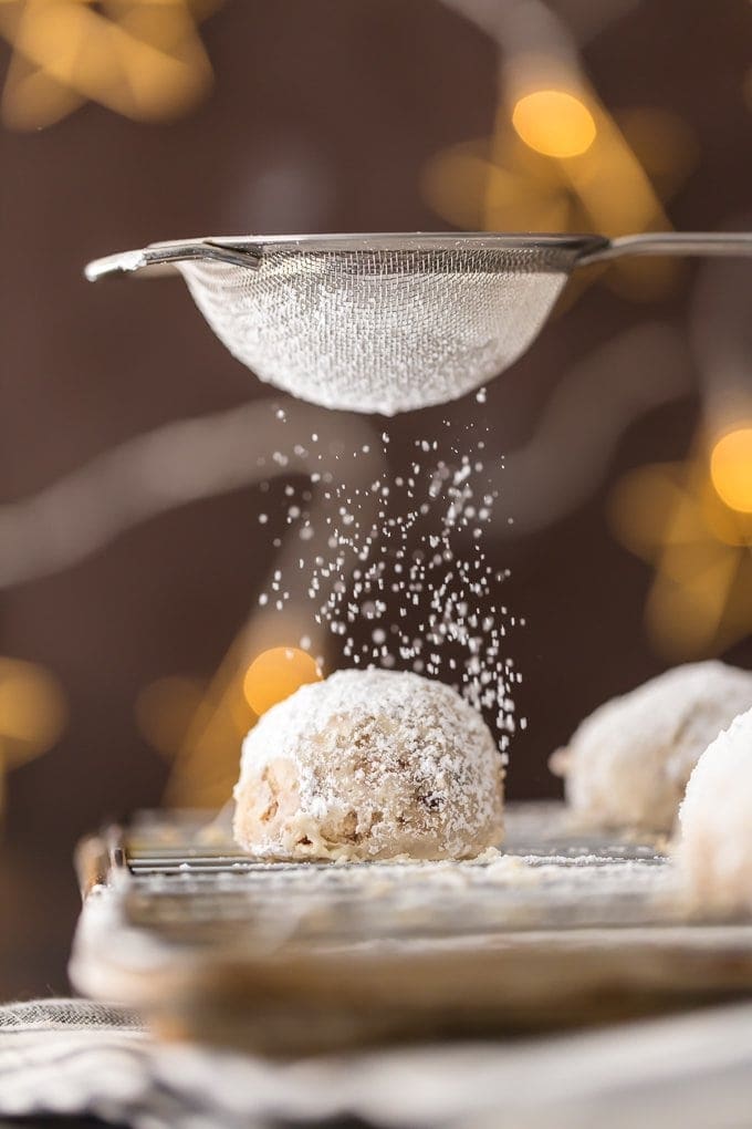 NUTELLA STUFFED SNOWBALL COOKIES being dusted with powdered sugar