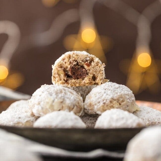 stack of NUTELLA STUFFED SNOWBALL COOKIES with a bite taken out of the one on the top