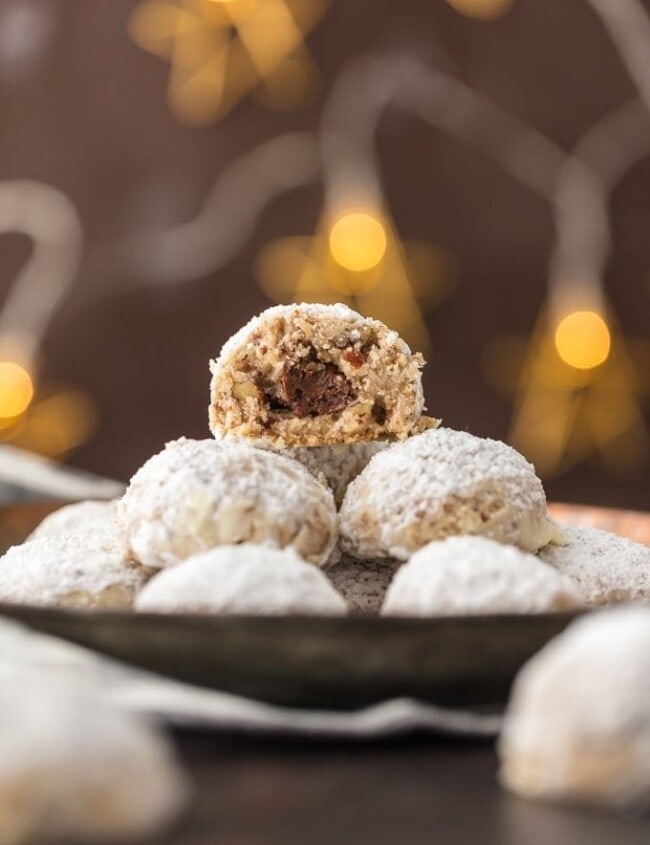 stack of NUTELLA STUFFED SNOWBALL COOKIES with a bite taken out of the one on the top