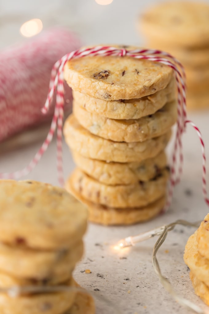 Stacks of orange cranberry shortbread cookies wrapped in red and white string