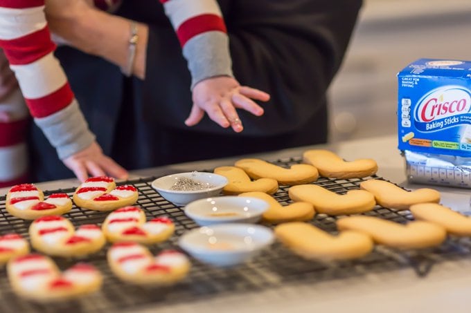 making Christmas sugar cookies: baby's hand reaching down toward a cooling rack full of candy cane cut out Christmas cookies