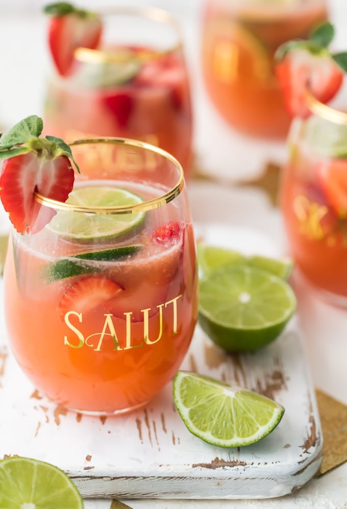 Glass of strawberry margarita punch garnished with sliced strawberry and lime