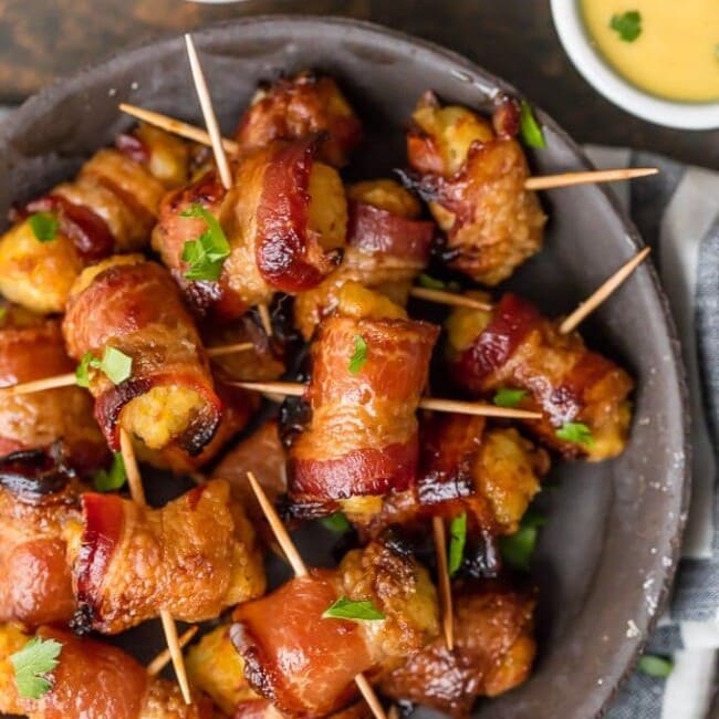 Bacon Wrapped Tater Tots are a must make appetizer for any celebration. You should make a triple batch of these SWEET & SPICY BACON WRAPPED TATER TOTS because they're always gone in seconds! Spices and and a little sweetness make this easy bacon wrapped appetizer a favorite for the holidays and tailgating. Tater Tots have never been better. SO ADDICTING!