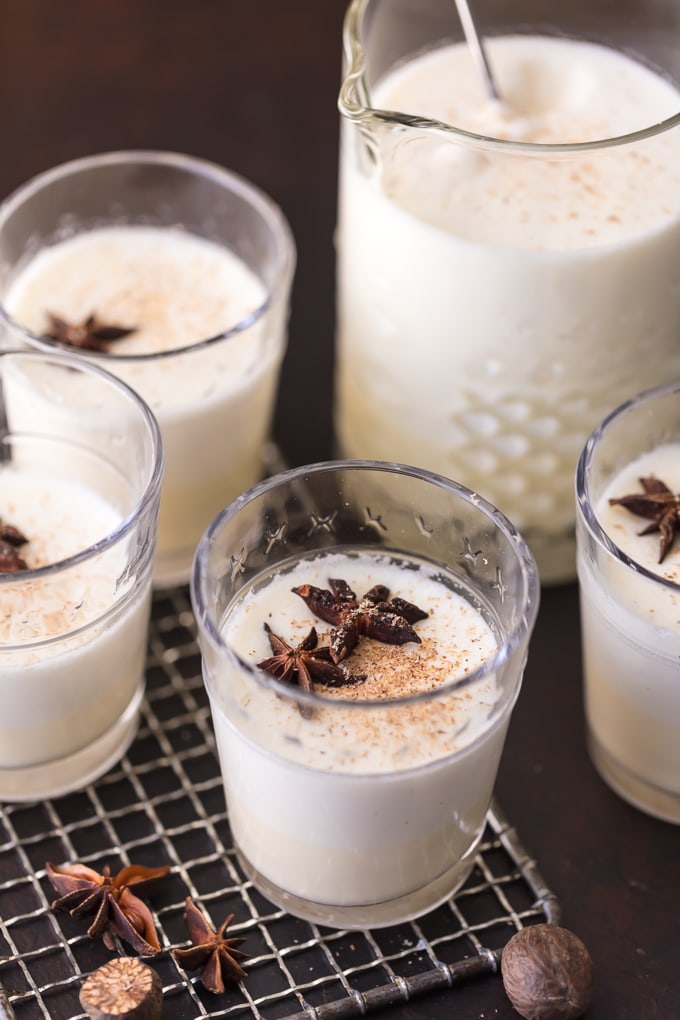 glasses and a pitcher full of traditional eggnog, made at home