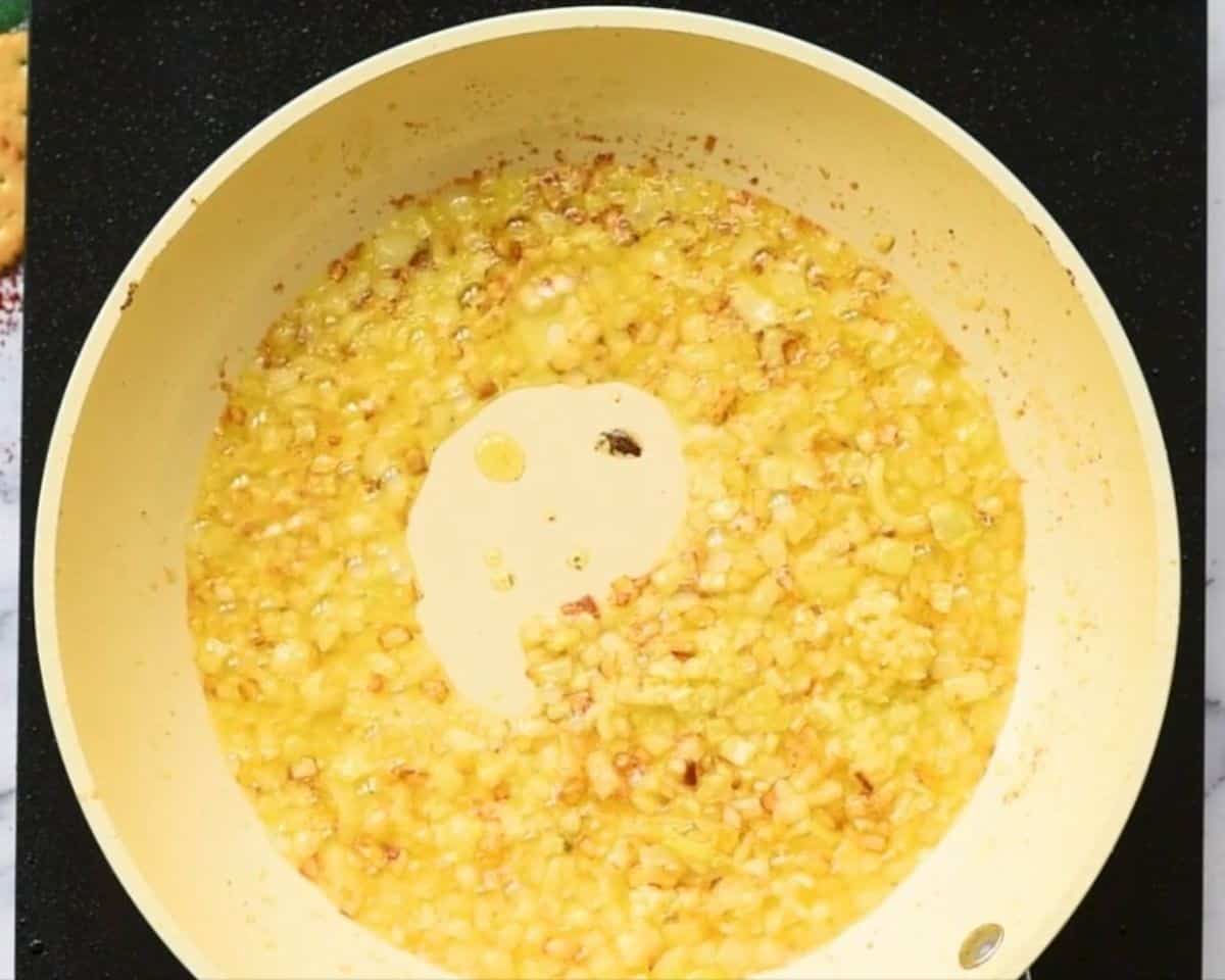 Sauteeing onions and garlic in a white skillet.