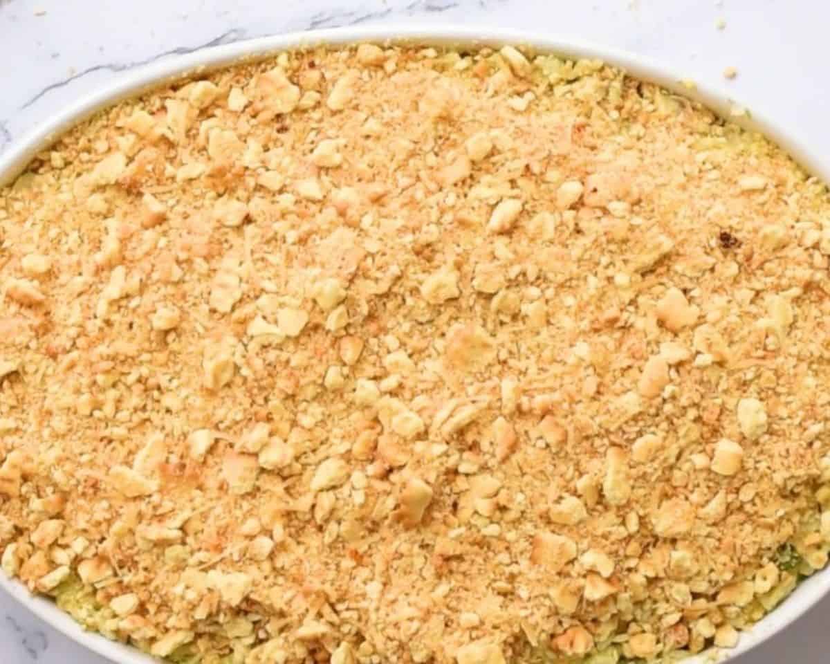 Adding the Ritz cracker topping to the casserole.