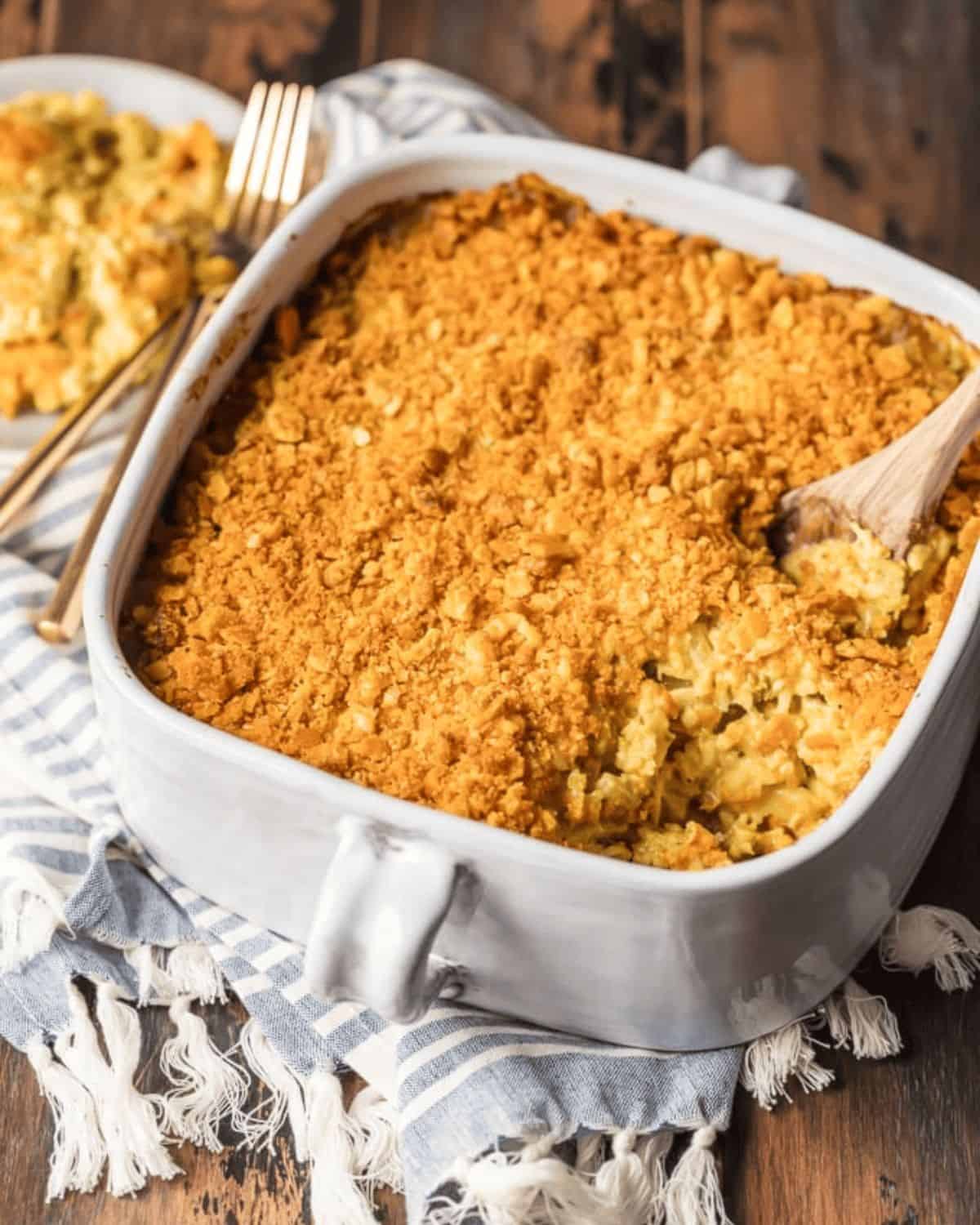 Chicken and rice casserole in a white casserole dish with a wooden spoon.