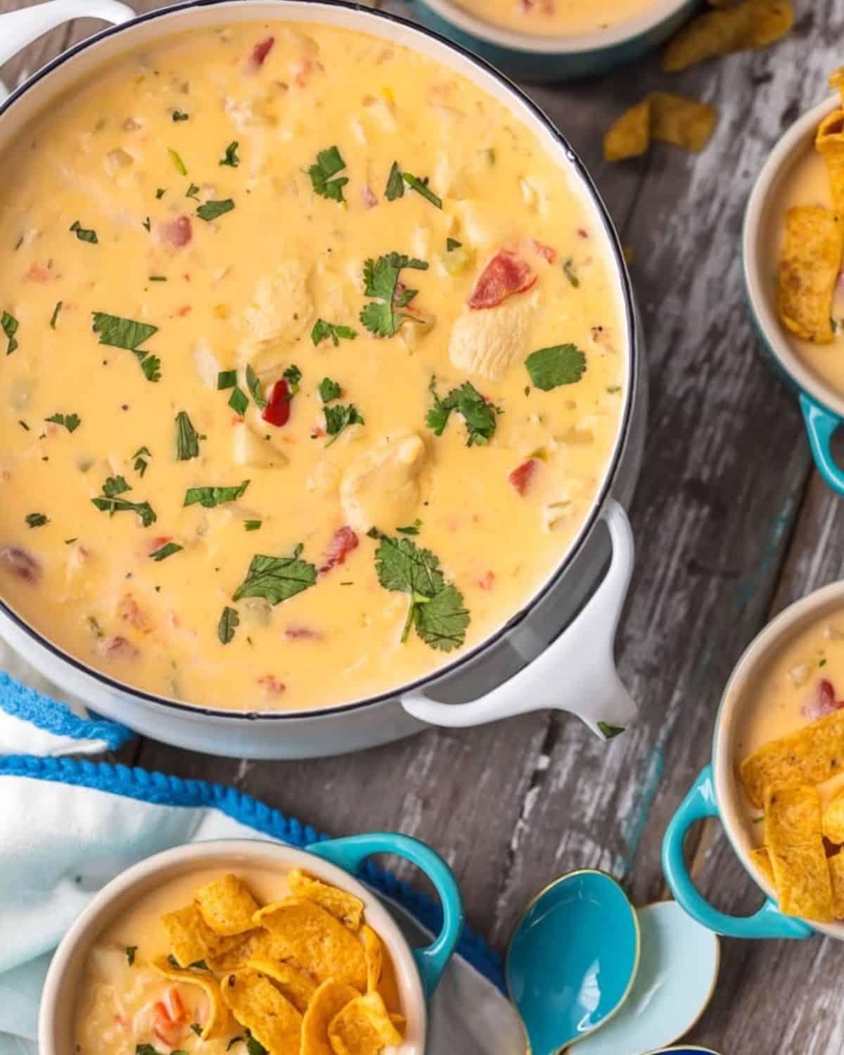 This MEXICAN CHEESY CHICKEN CHOWDER RECIPE is the ultimate Winter comfort food soup! Loaded with spicy tomatoes, green peppers, hash brown potatoes, garlic, onion, CHEESE, and more, this was an instant favorite at our house. Serve this cheesy chicken chowder with Fritos or tortilla chips and you're in business. SO GOOD. A white pot of Mexican cheesy chicken chowder.