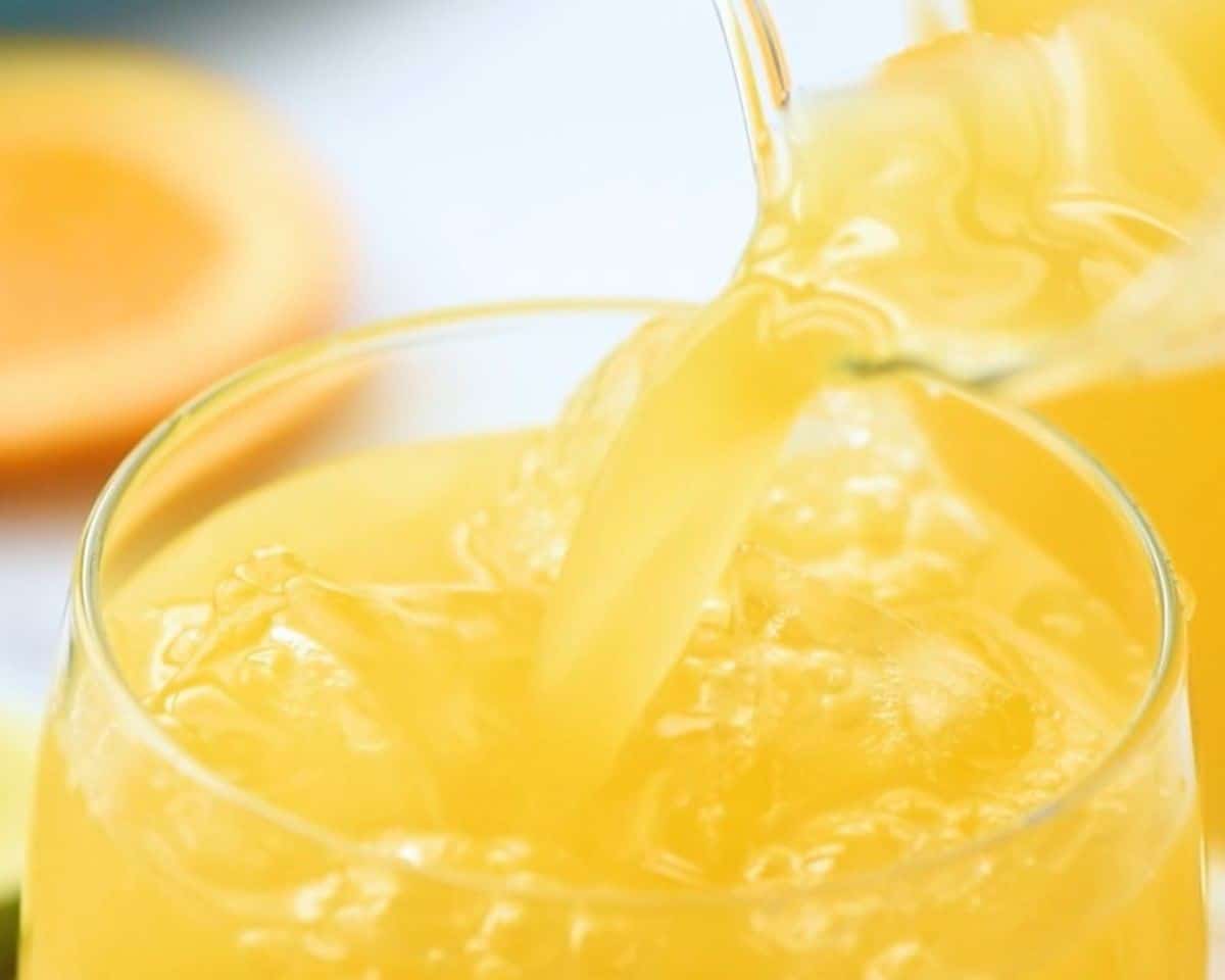 Adding the orange juice mixture to the glass with ice.