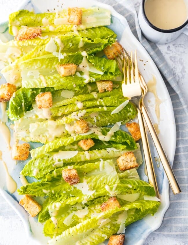 a bed of lettuce with croutons, cheese, and caesar dressing