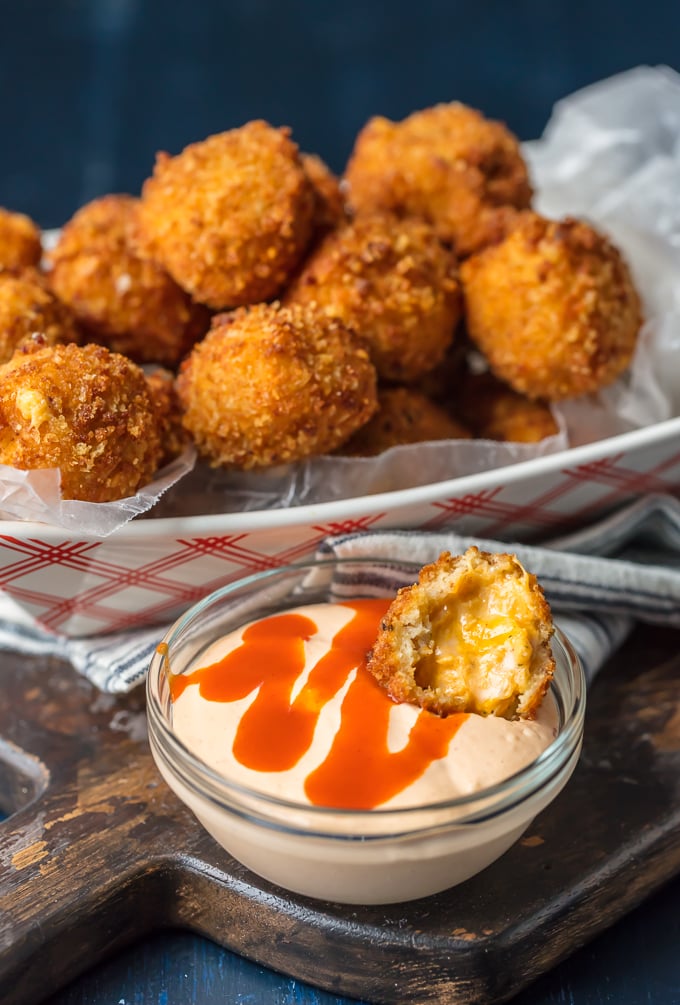 buffalo chicken dip bite in sauce and basket of bites behind it