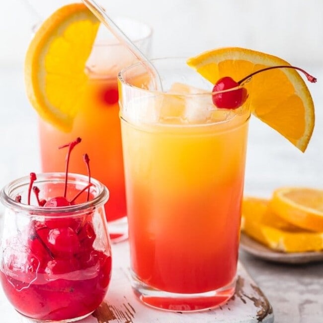 cocktails in glasses next to cherries and oranges