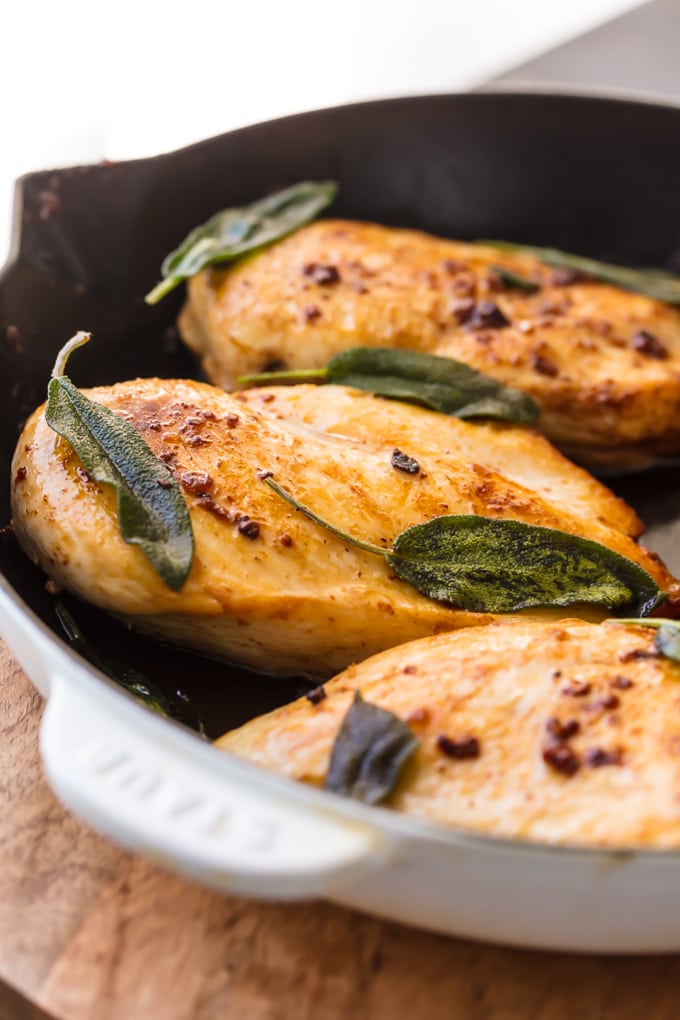 Close up of brine chicken breast topped with sage leaves