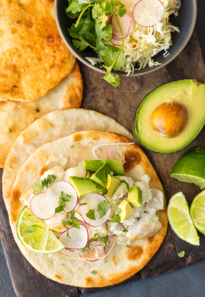 Fish tacos, avocado, lime, tortillas, and bowl of fresh ingredients