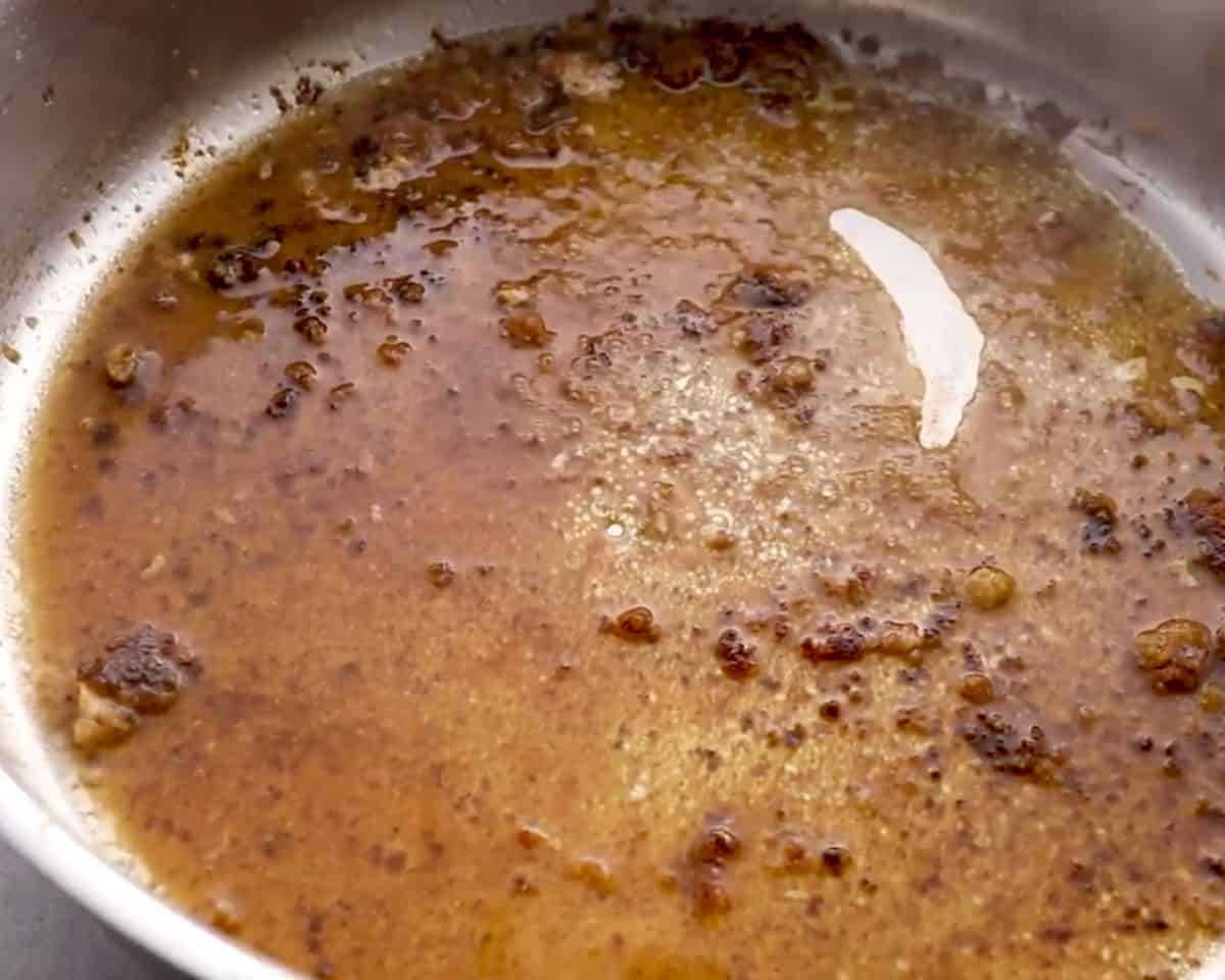 Chicken broth and pan drippings simmering in skillet to deglaze and build sauce flavor