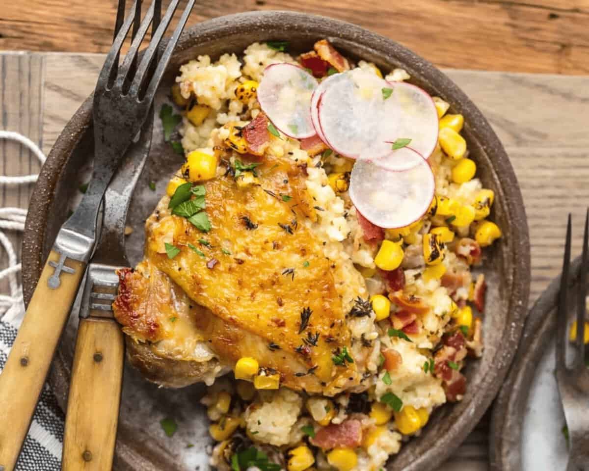 This LEMON BUTTER SALMON IN PARCHMENT is our favorite way to cook a healthy and delicious seafood meal at home! Asparagus and onion topped with succulent salmon, lemons, and thyme, and drizzled in lemon butter. SO EASY and amazingly good! finished plate of chicken couscous with bacon and corn