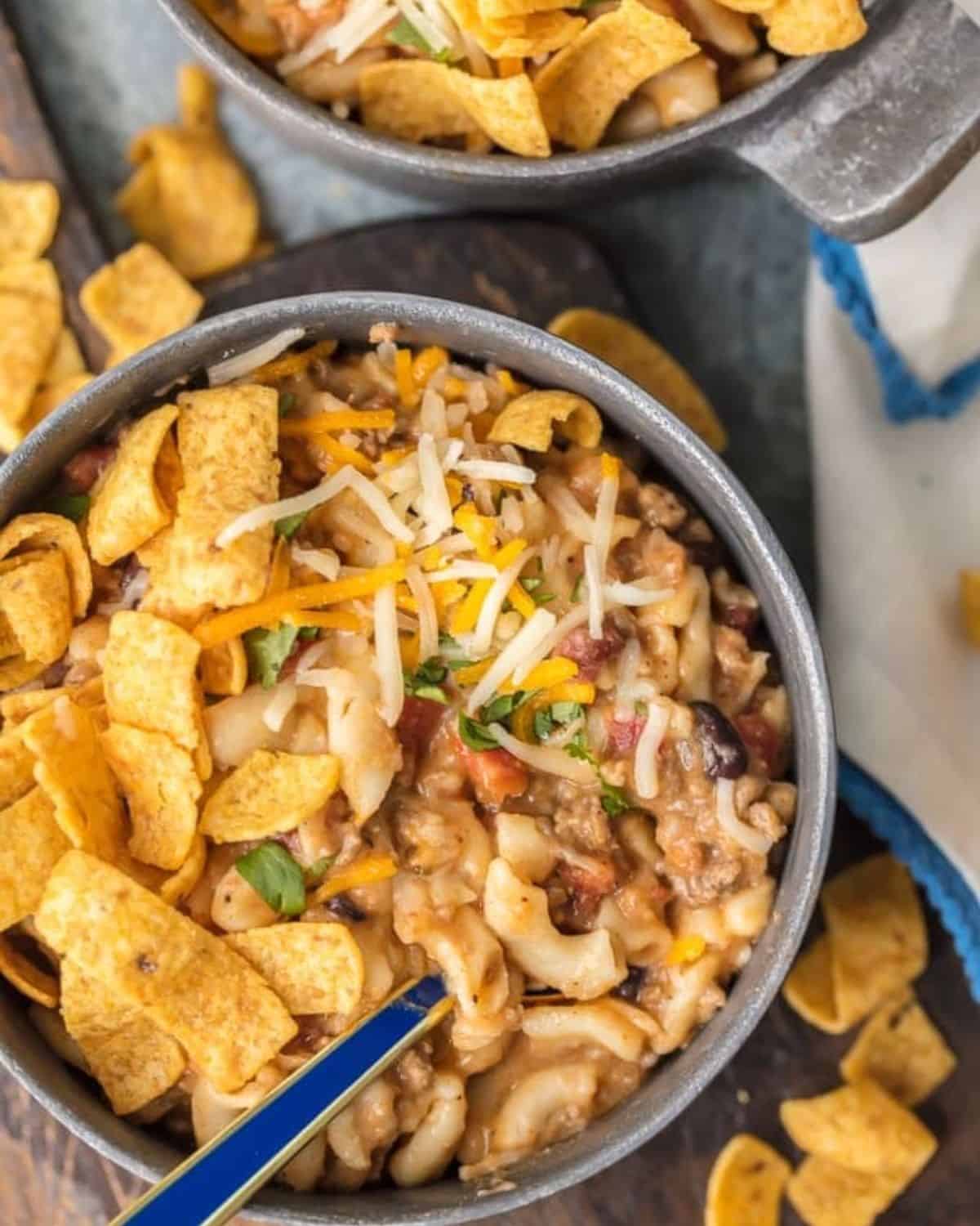 Instant Pot Chili Mac will be your new go-to favorite comfort food! This amazing Chili Mac Recipe is loaded with beef, cheese, beans, tomatoes, and so much more. Kids and adults alike will be back for seconds. We love to top our pressure cooker chili mac with fritos, sour cream, and lots of cheese. There's nothing like a bowl of easy Chili Mac and Cheese on a chilly night. Bowl of Instant Pot Chili Mac topped with Fritos.